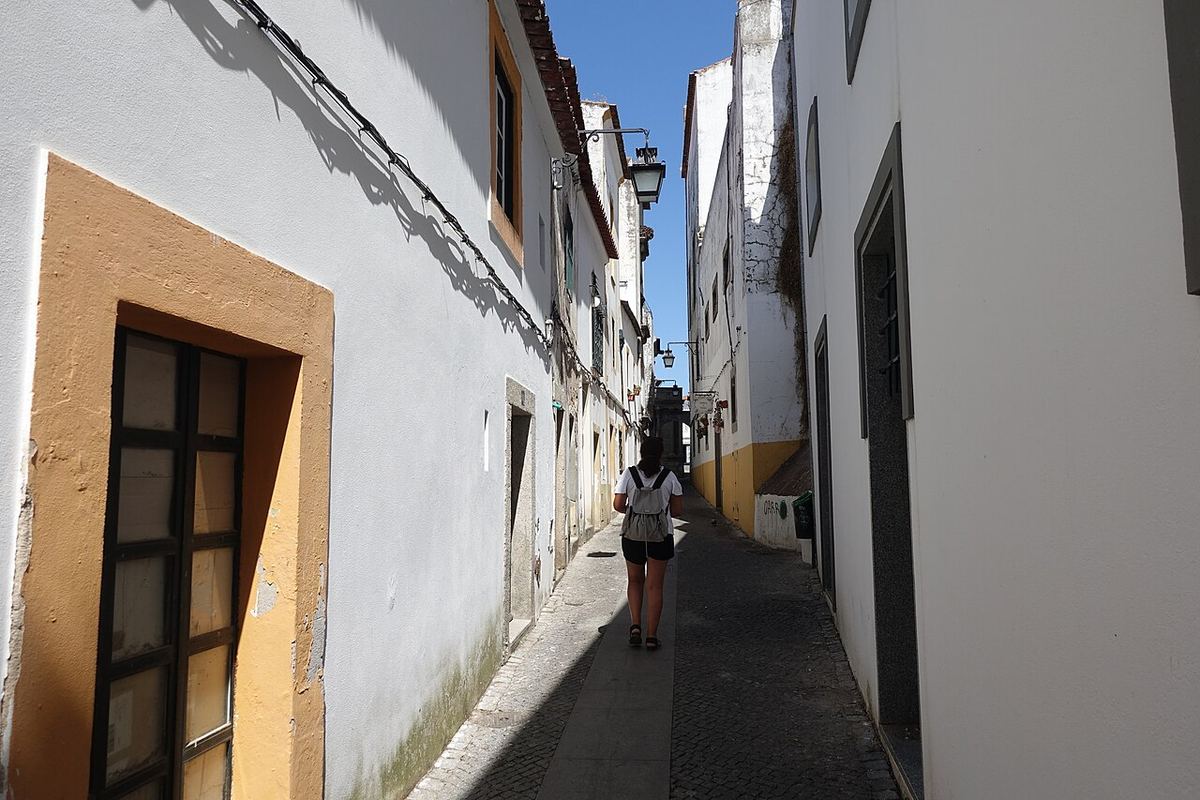 Rua estreita de casas caiadas de branco e amarelo no centro histórico de Évora
