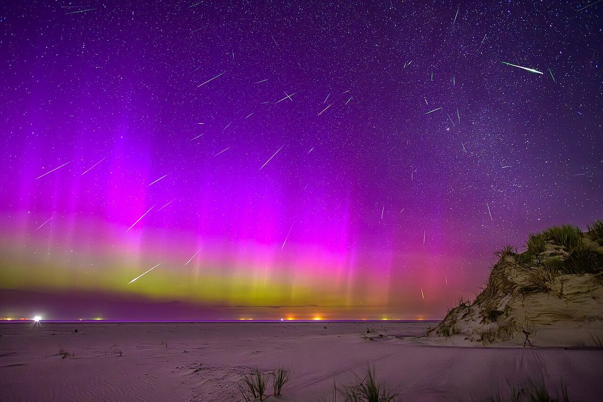 Vários meteoros das Perseidas a riscar o céu sobre um horizonte com aurora