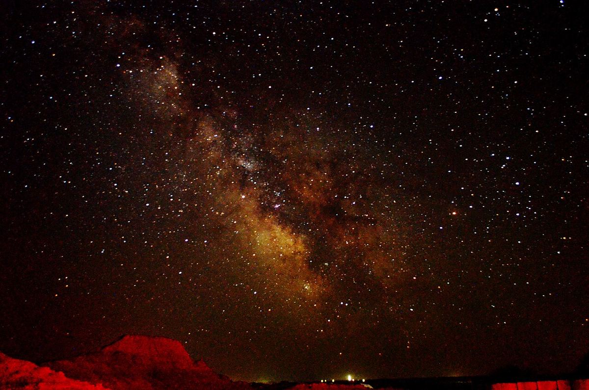Via Láctea alaranjada e densa de estrelas num céu sem poluição luminosa