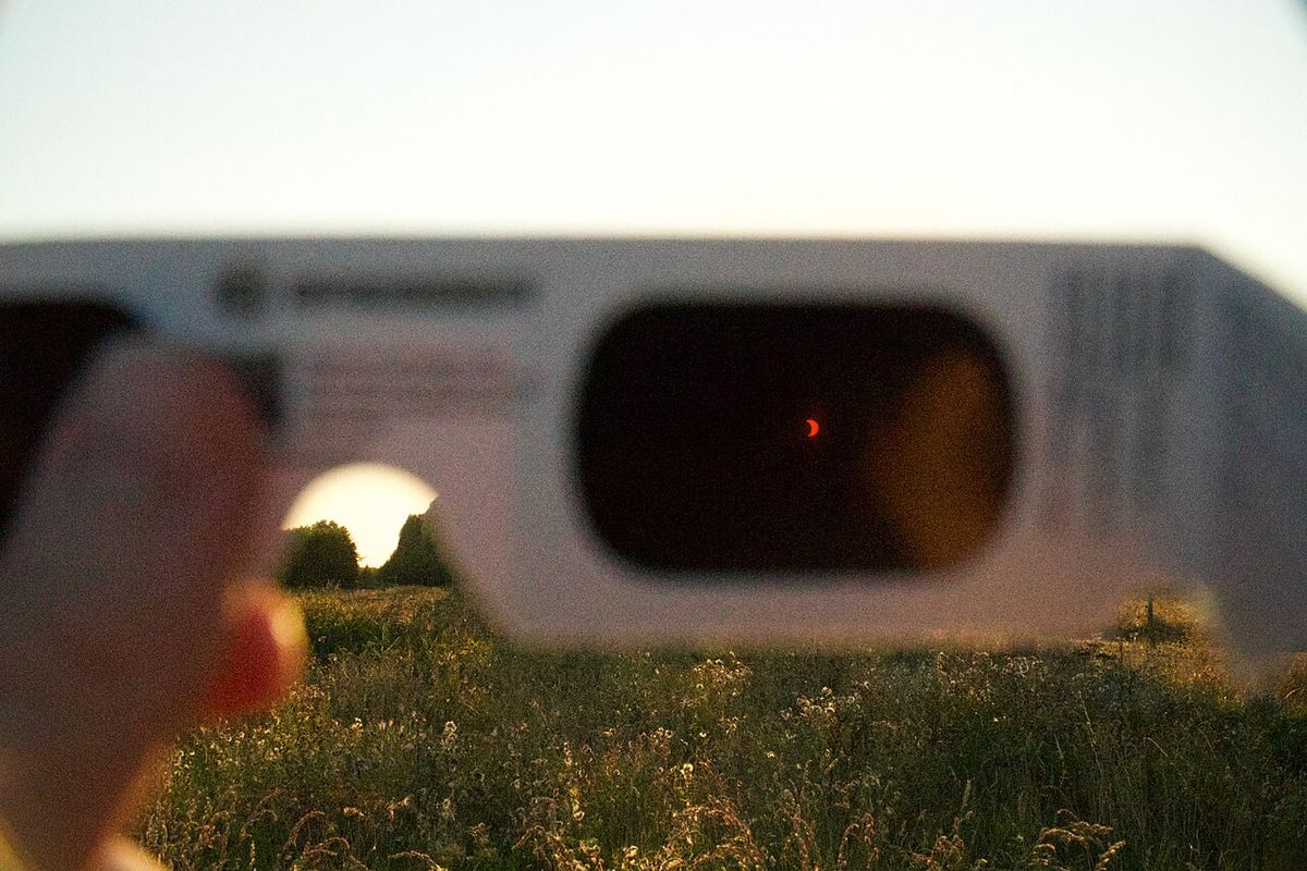 Eclipse parcial do Sol visto através de óculos de eclipse com filtro certificado