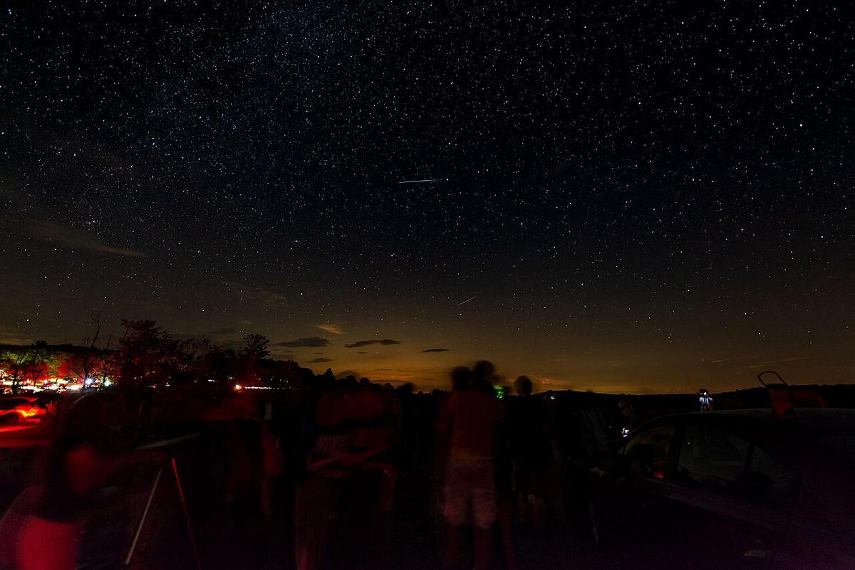 Miniatura: Grupo de pessoas a observar o céu estrelado ao anoitecer num campo aberto
