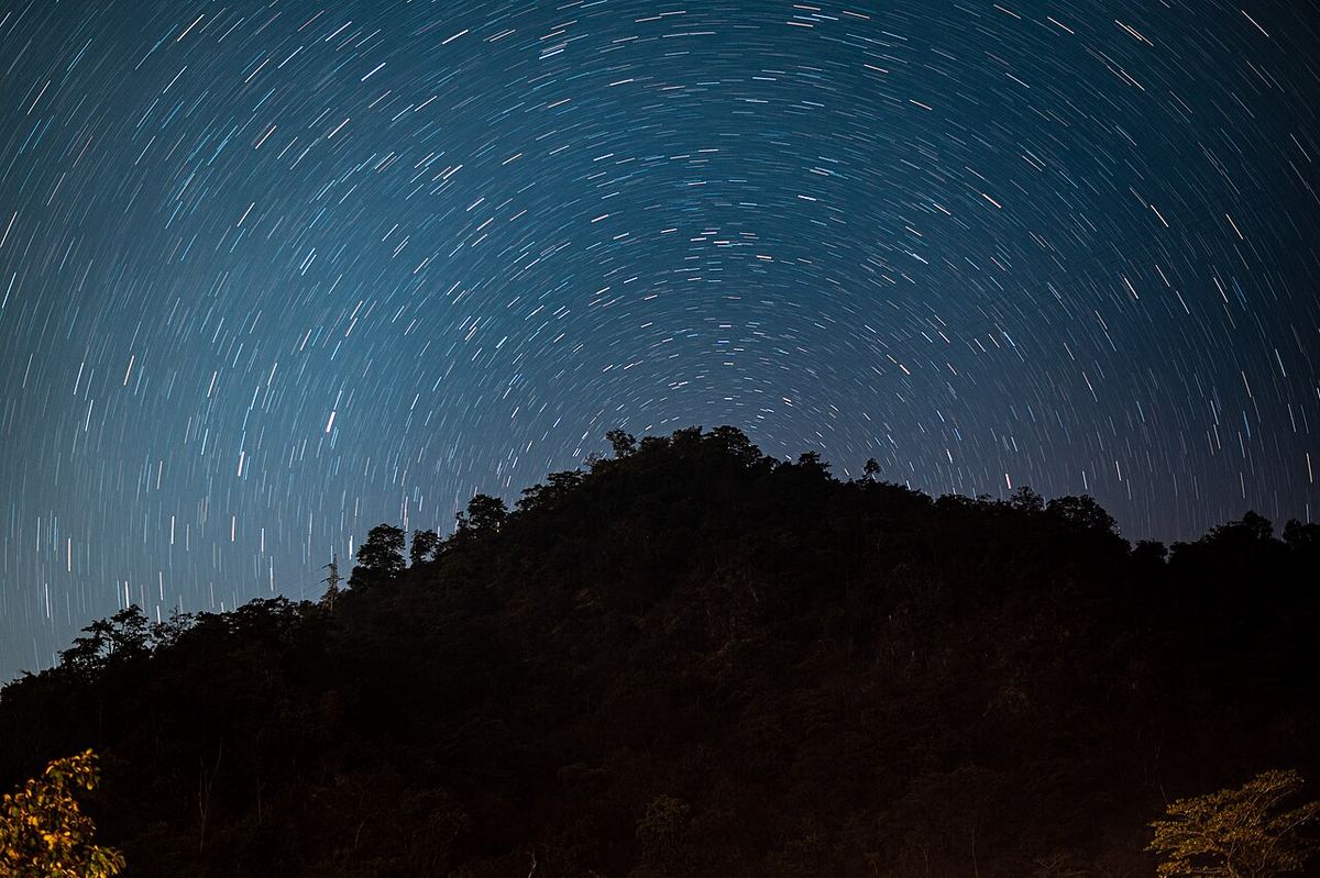 Miniatura: Rastos circulares de estrelas em torno do polo celeste sobre um monte escuro