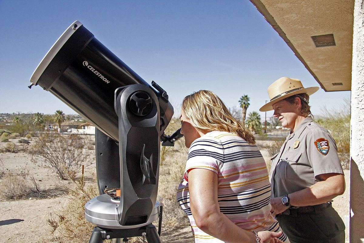 Miniatura: Pessoas a observar um eclipse parcial através de um telescópio com filtro solar na objetiva