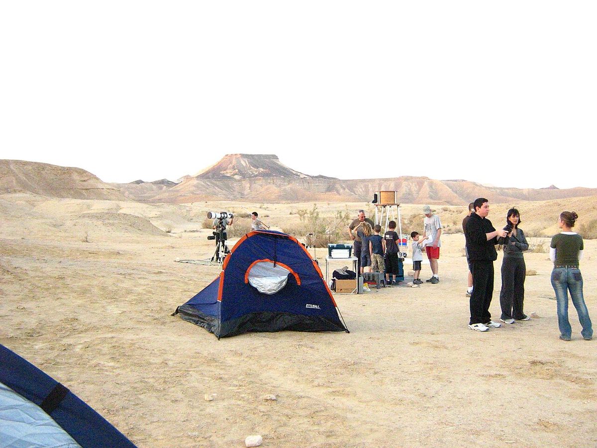 Miniatura: Grupo de observadores com telescópios e uma tenda num local desértico ao fim da tarde